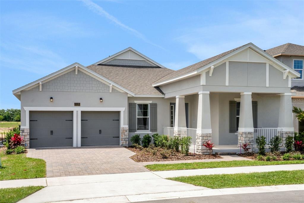A single-story house with a two-car garage, stone accents, and a covered front porch — 15160 TEA TREE DRIVE, WINTER GARDEN, FL