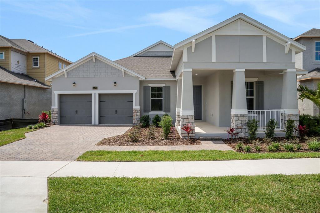 A single-story suburban house with a two-car garage, stone accents, and a covered front porch — 15160 TEA TREE DRIVE, WINTER GARDEN, FL
