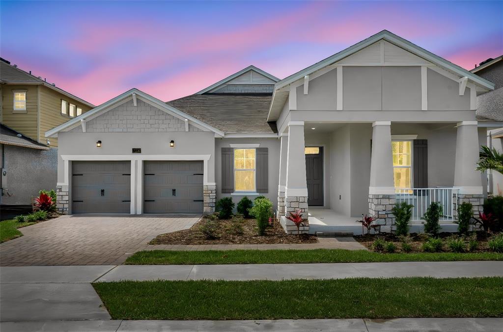 A single-story house with a two-car garage, stone accents, and a covered front porch — 15160 TEA TREE DRIVE, WINTER GARDEN, FL