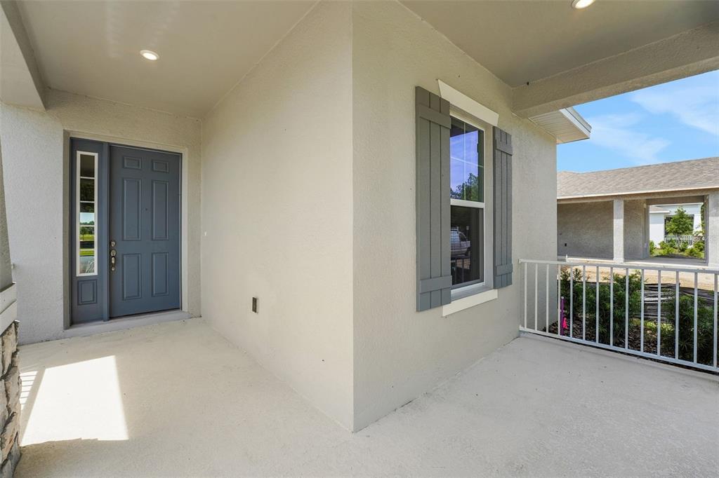 A covered front porch features a blue door, a window with shutters, and white railings — 15160 TEA TREE DRIVE, WINTER GARDEN, FL
