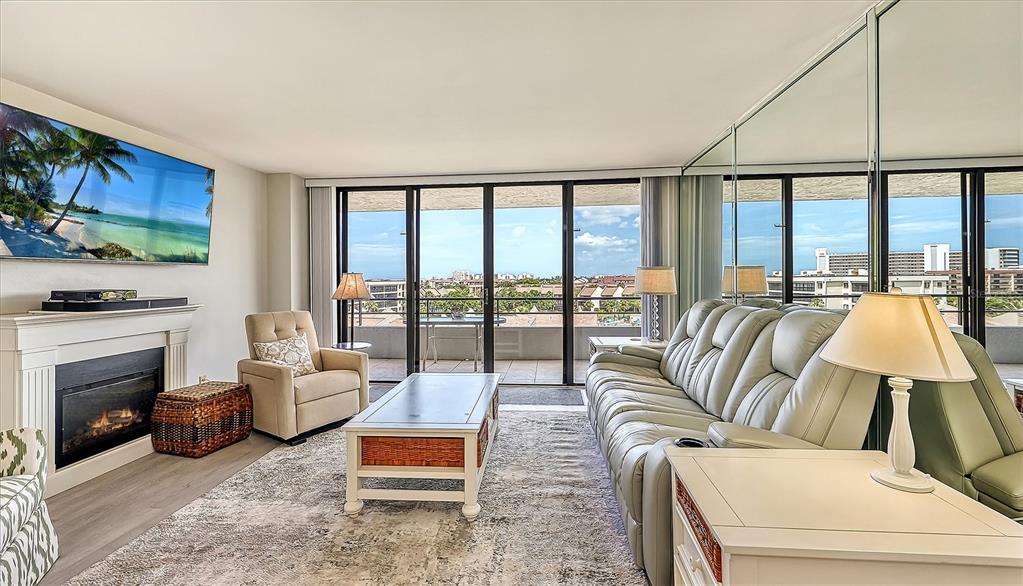 A living room features a fireplace, a large sectional sofa, and a balcony with views — 6415 MIDNIGHT PASS ROAD UNIT 602, SARASOTA, FL