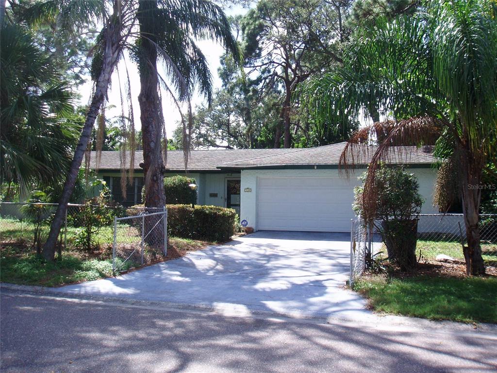 A single-story house with a white garage door and palm trees in the front yard — 120 SW MONROE CIRCLE N, ST PETERSBURG, FL