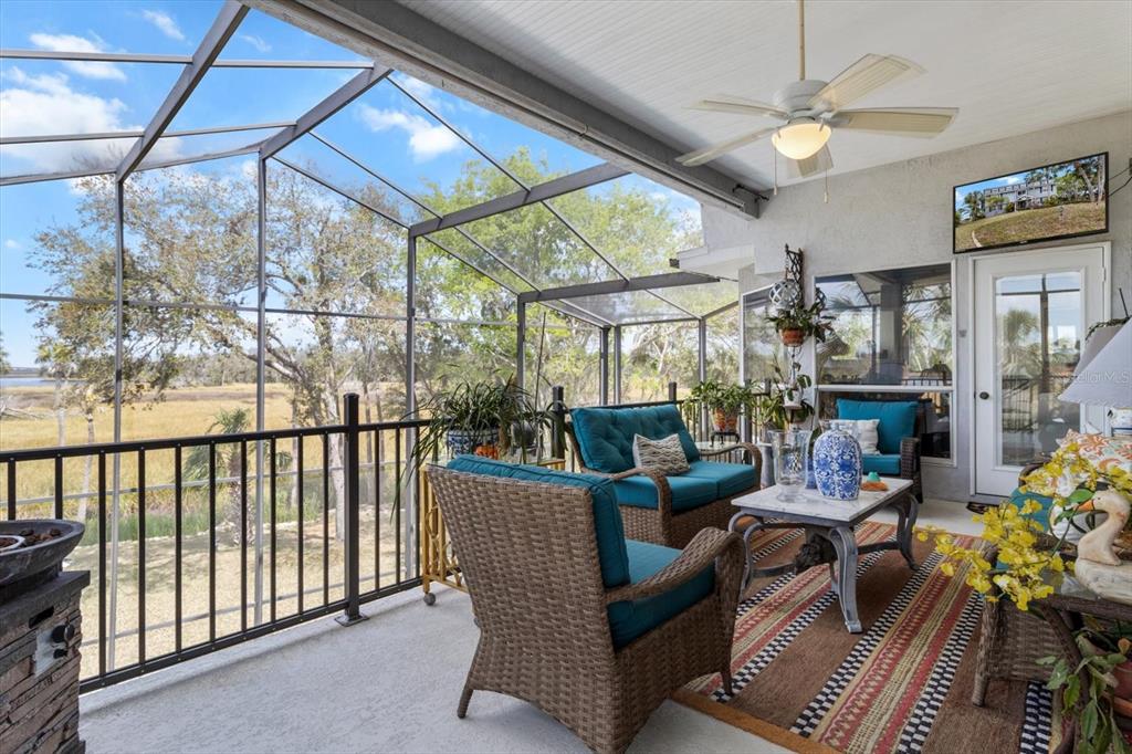 A screened-in patio features wicker furniture, a ceiling fan, and a view of the marsh — 11927 W TIMBERLANE DRIVE, HOMOSASSA, FL