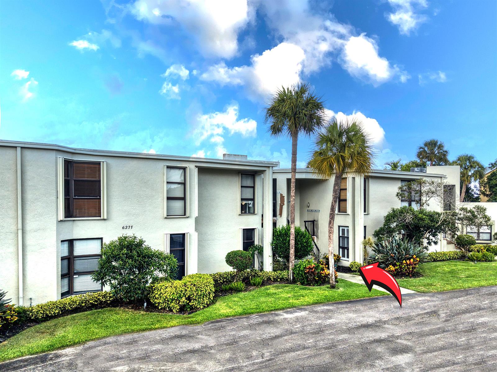 A two-story apartment building exterior with palm trees and landscaping under a blue sky — 6371 La Costa Drive # 104, Boca Raton FL 33433, BOCA RATON, FL