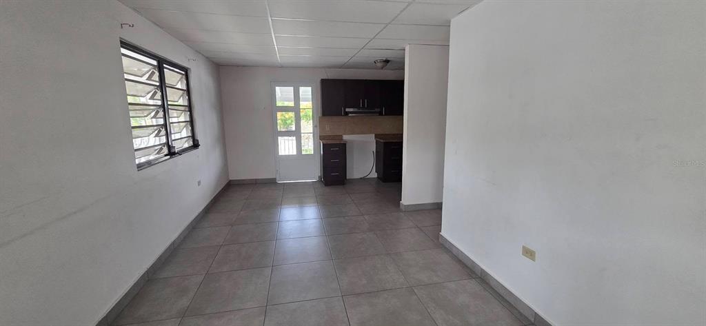 A room with gray tile flooring, white walls, a window with louvers, and dark cabinets — Calle 15 C-3 SAN FERNANDO, BAYAMON, PR