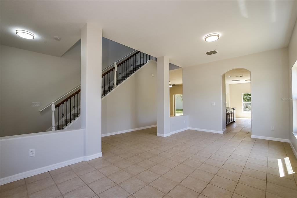 An interior view of a living area with tile flooring, a staircase, and arched doorways — 12104 CITRUSWOOD DRIVE, ORLANDO, FL
