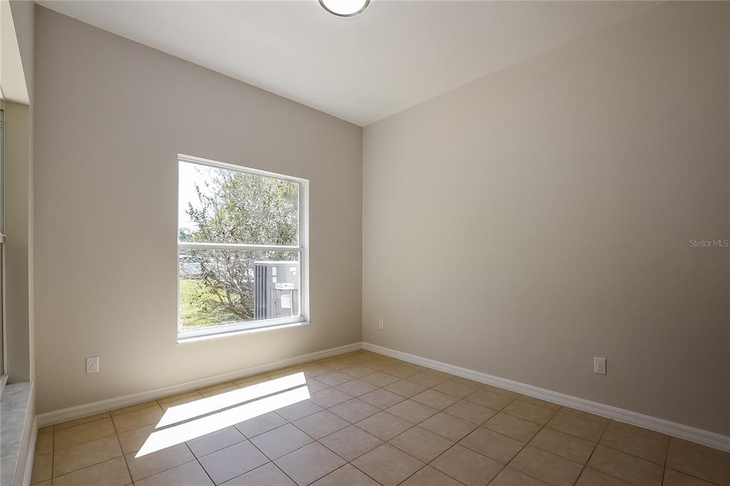 An empty room with beige walls, tile flooring, and a single window — 12104 CITRUSWOOD DRIVE, ORLANDO, FL