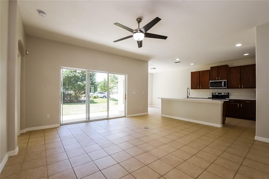 An open-concept kitchen and living area features tile flooring, a ceiling fan, and sliding doors — 12104 CITRUSWOOD DRIVE, ORLANDO, FL