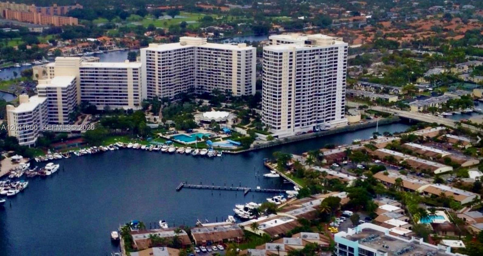 An aerial view of waterfront high-rise apartment buildings with a pool and boat docks — 500 Three Islands Blvd # 223, Hallandale Beach FL 33009, HALLANDALE BEACH, FL