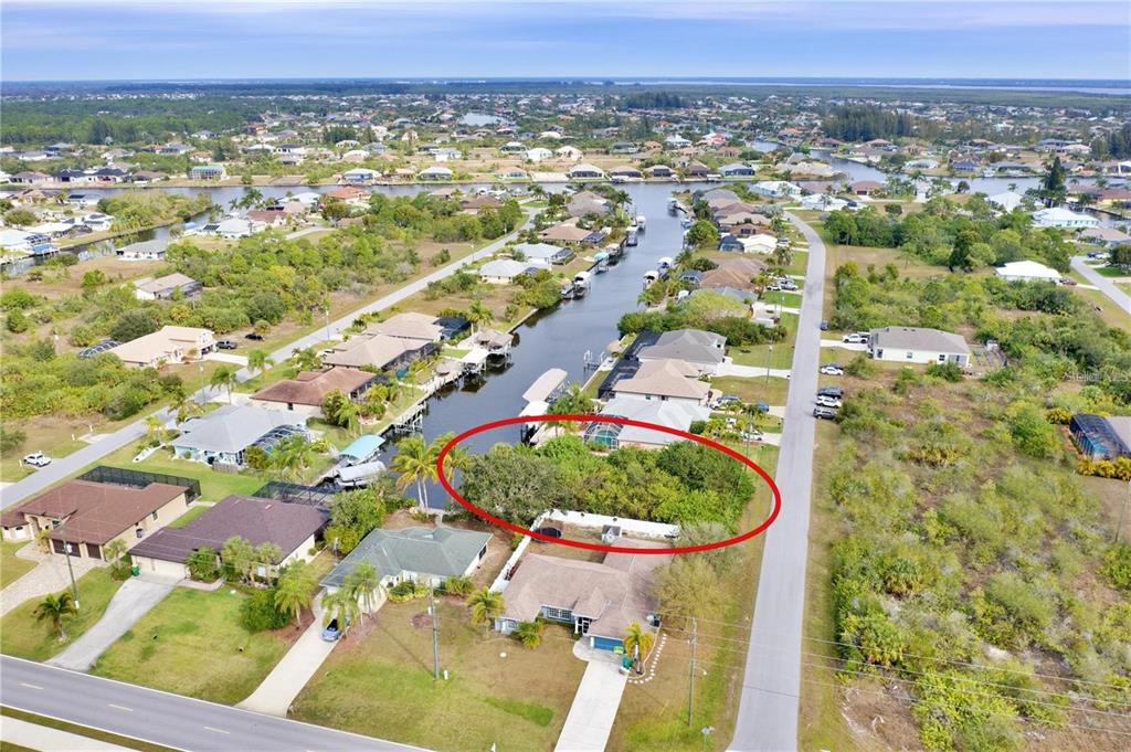 An aerial view shows a vacant, tree-covered residential lot situated along a canal — 9180 SPRING CIRCLE, PORT CHARLOTTE, FL