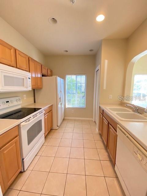 A kitchen with light wood cabinets, white appliances, tile flooring, and a window — 12996 COYOTE LANE, VENICE, FL