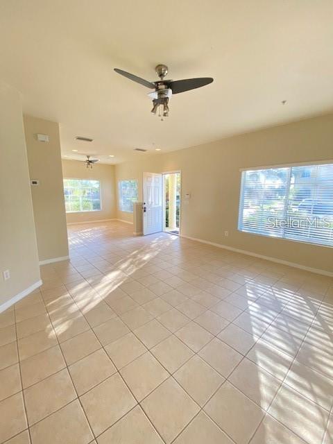 An open-concept living area features light-colored tile flooring, a ceiling fan, and large windows — 12996 COYOTE LANE, VENICE, FL
