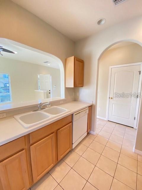 A kitchen features light wood cabinets, white countertops, a double sink, and a white dishwasher — 12996 COYOTE LANE, VENICE, FL