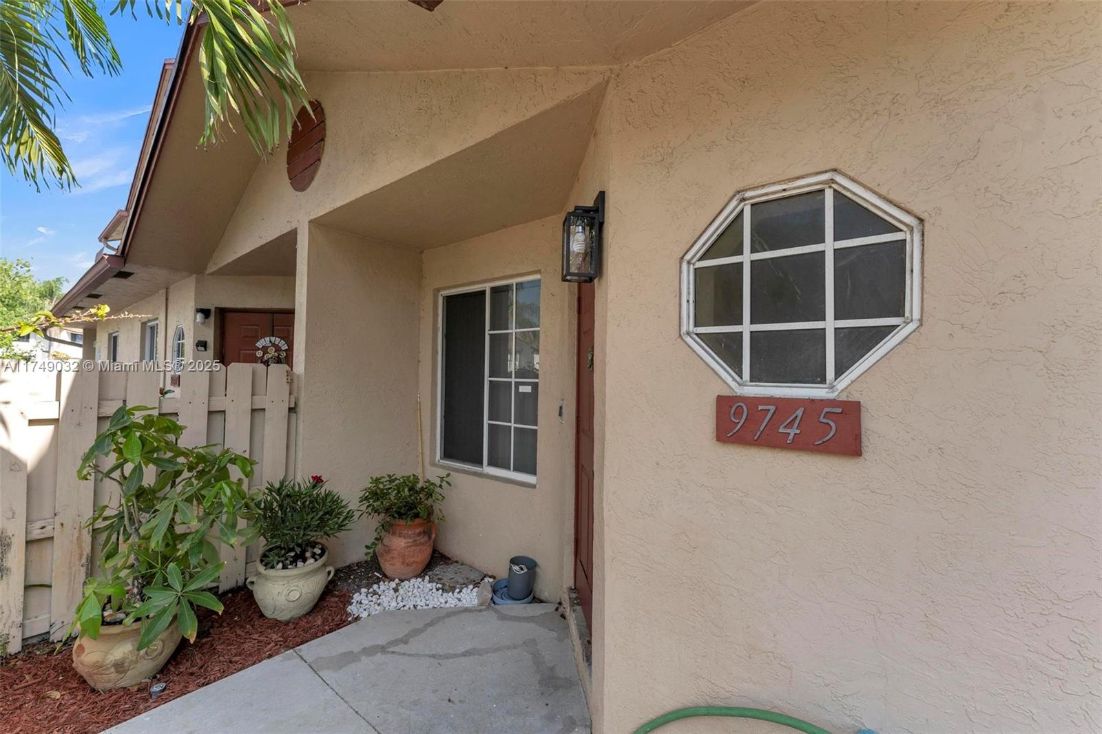 The exterior view shows a tan stucco home entrance with an octagonal window and plants — 9745 NW 37th St # 9745, Sunrise FL 33351, SUNRISE, FL