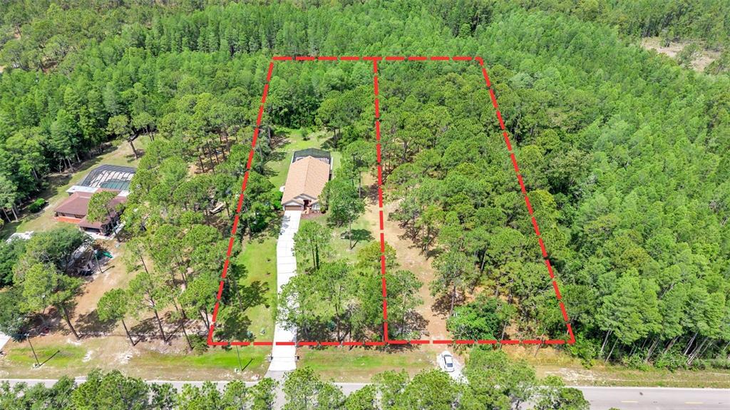 An aerial view shows a house with a driveway situated on a wooded lot — 13409 SWEET HILL ROAD, POLK CITY, FL