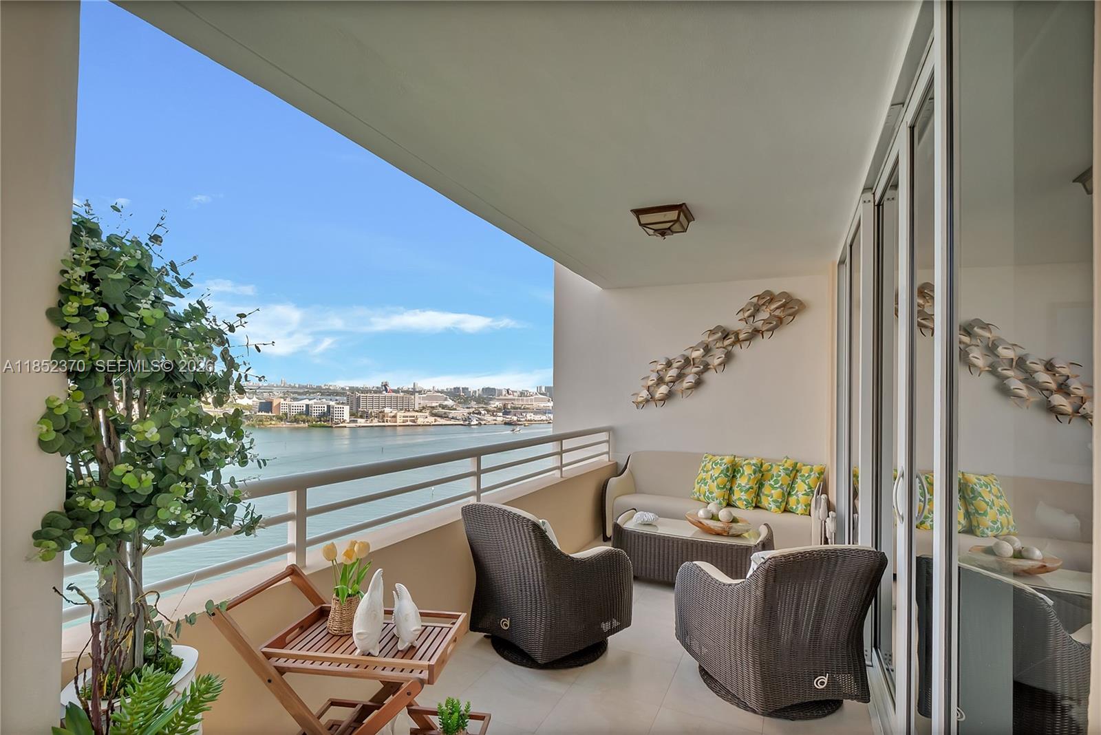 A balcony with wicker furniture and a view of the water and city skyline — 848 Brickell Key Dr # 1906, Miami FL 33131, MIAMI, FL