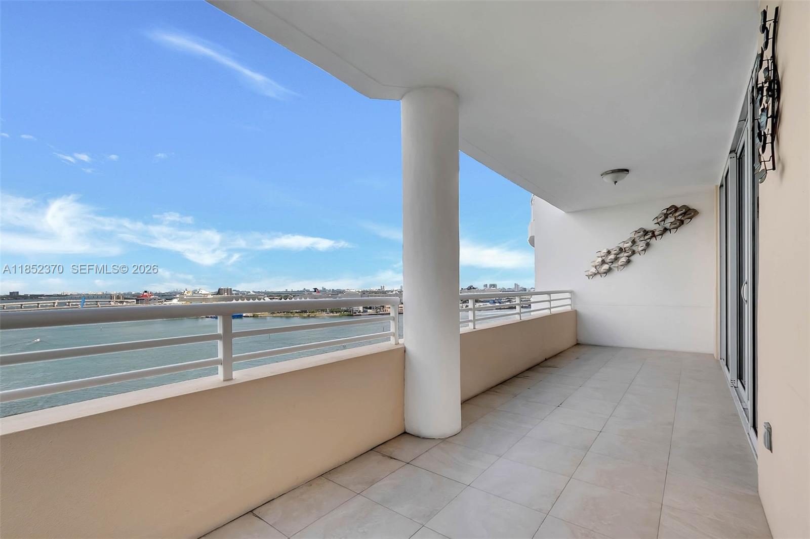 A balcony with tile flooring, a white support pillar, and a metal fish wall sculpture — 848 Brickell Key Dr # 1906, Miami FL 33131, MIAMI, FL