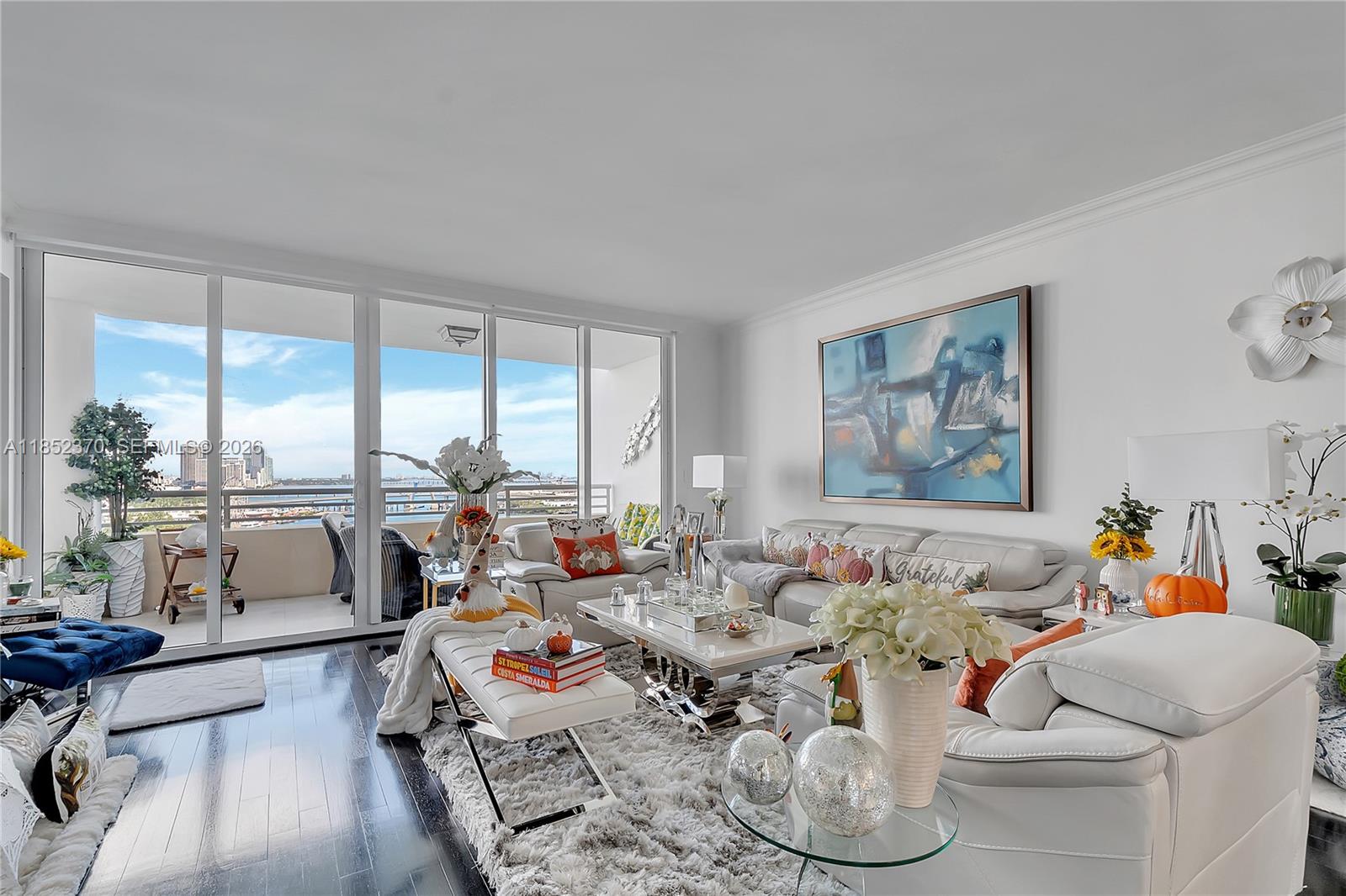 A bright living room features white leather furniture, a glass coffee table, and a balcony view — 848 Brickell Key Dr # 1906, Miami FL 33131, MIAMI, FL