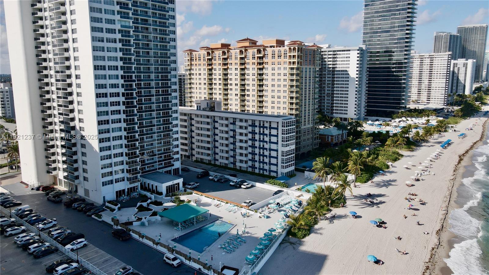 An aerial view shows high-rise apartment buildings, a swimming pool, and a sandy beach — 3140 S Ocean Dr # 512, Hallandale Beach FL 33009, HALLANDALE BEACH, FL