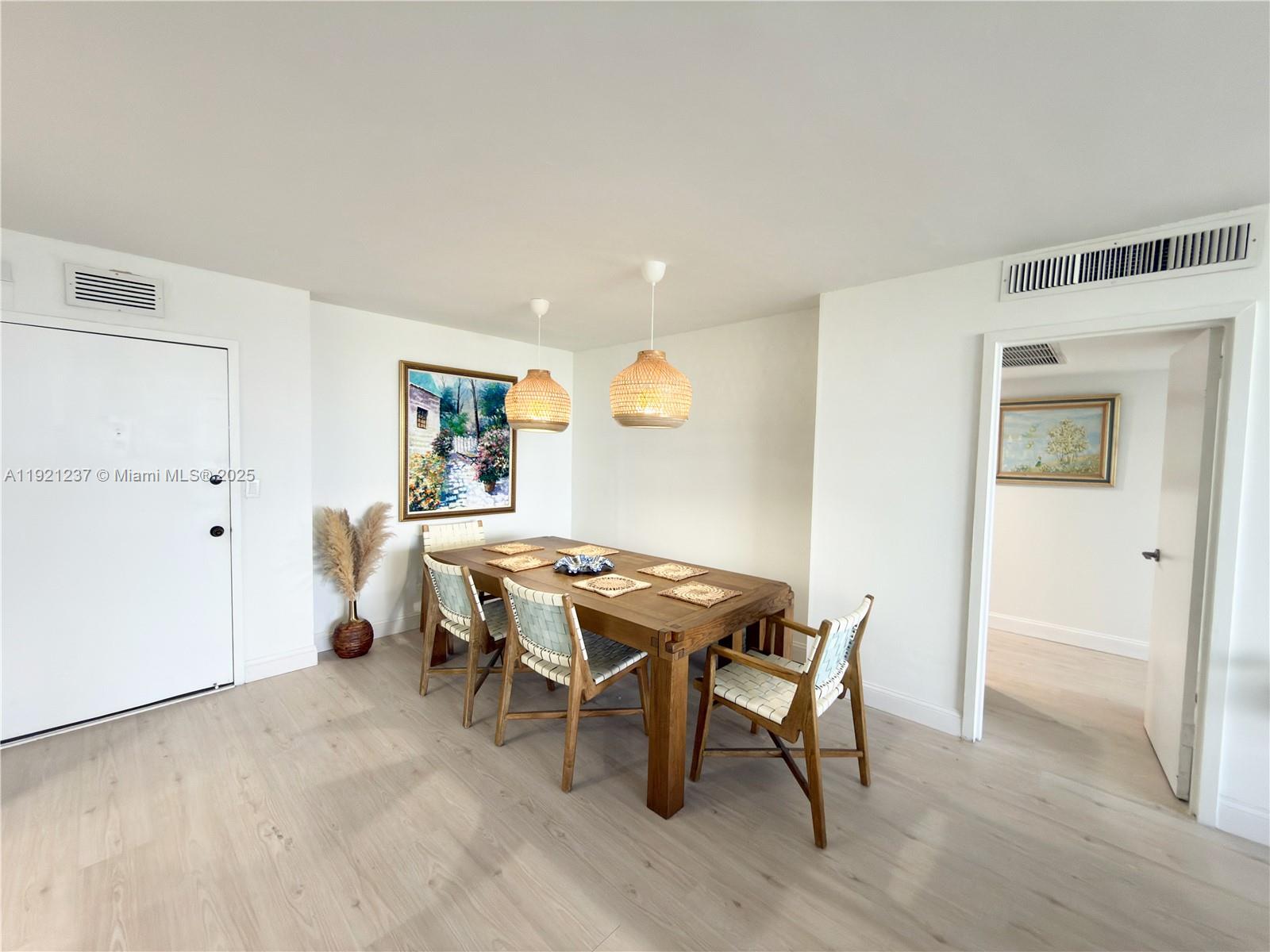 A dining room features a wooden table, woven chairs, pendant lights, and light wood flooring — 3140 S Ocean Dr # 512, Hallandale Beach FL 33009, HALLANDALE BEACH, FL