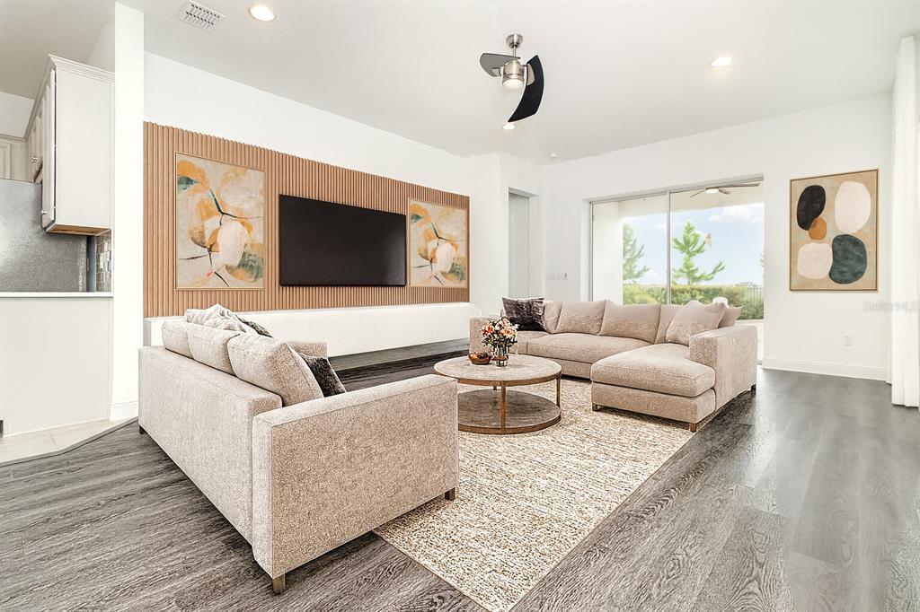 A living room features a slatted wood accent wall, a sectional sofa, and wood flooring — 15701 VETTA DRIVE, MONTVERDE, FL