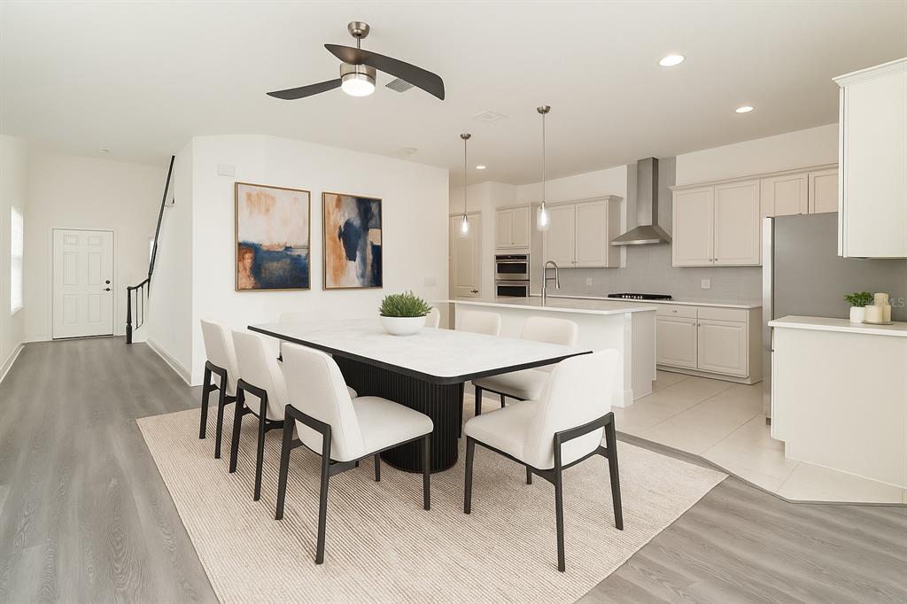A dining area with a modern table and chairs sits adjacent to an open kitchen — 15701 VETTA DRIVE, MONTVERDE, FL