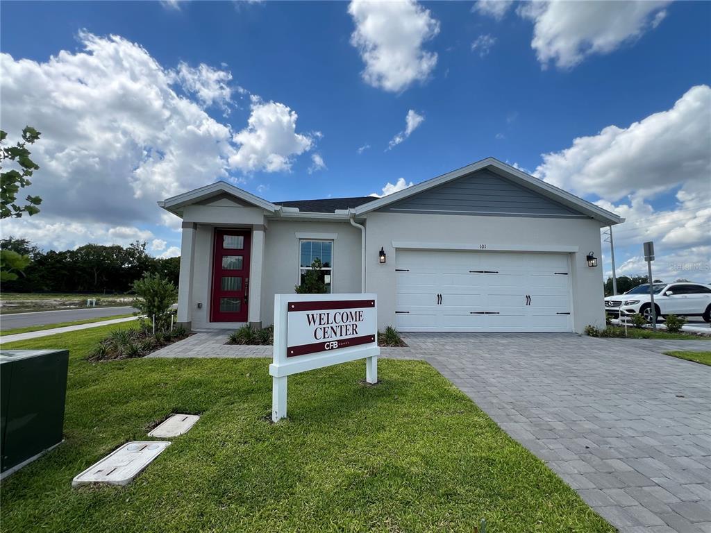 A single-story house with a white garage, red front door, and a welcome center sign — 280 ELENA LAVIN CIRCLE, ORLANDO, FL