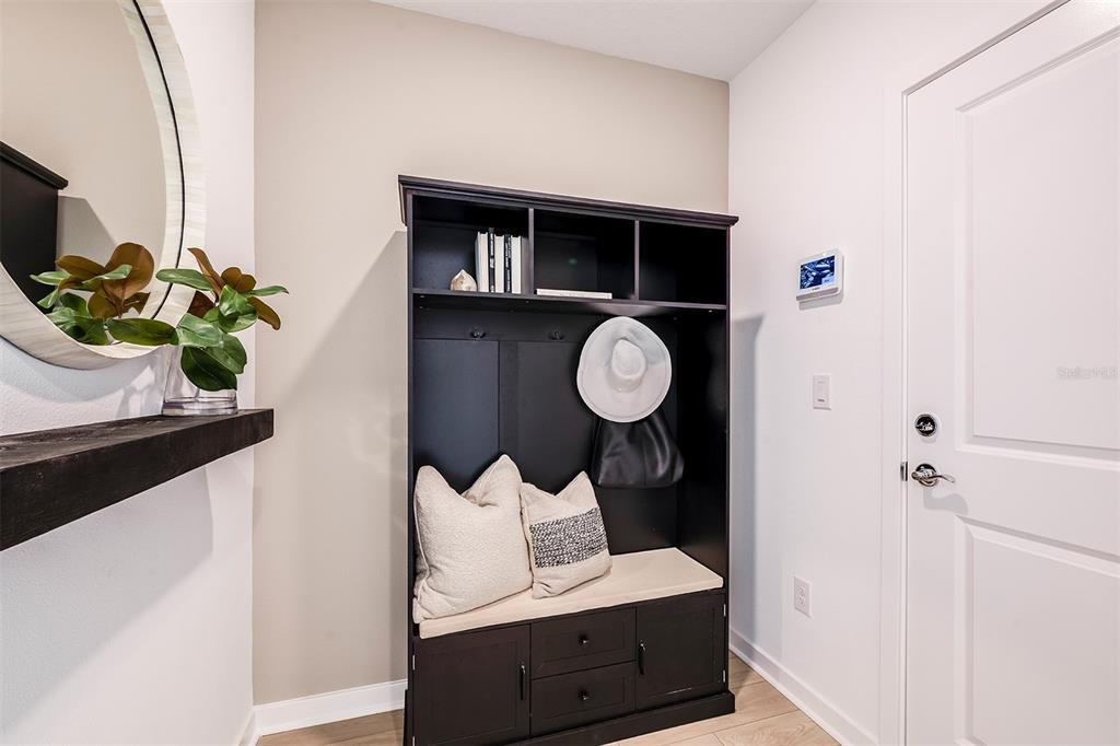 An entryway features a black hall tree, a floating shelf, a round mirror, and a door — 1420 HAMILTON WAY, LAKE ALFRED, FL