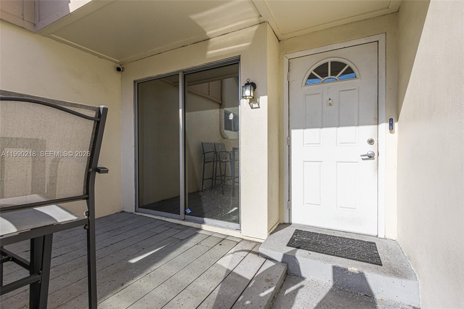 A white front door and sliding glass door open onto a small wooden deck — 835 NW 80th Ter # 11, Plantation FL 33324, PLANTATION, FL