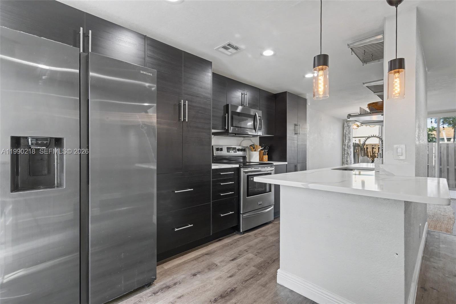 A modern kitchen features dark wood cabinetry, stainless steel appliances, and a white quartz island — 835 NW 80th Ter # 11, Plantation FL 33324, PLANTATION, FL