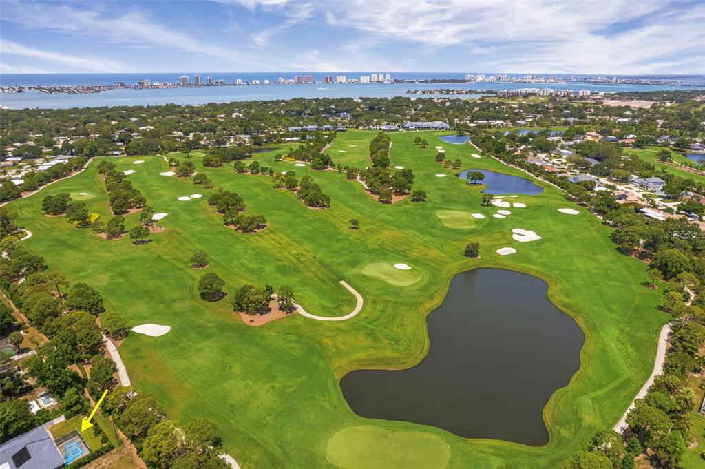 An aerial view shows a golf course with a large pond and a residential house — 656 MEHLENBACHER ROAD, BELLEAIR, FL