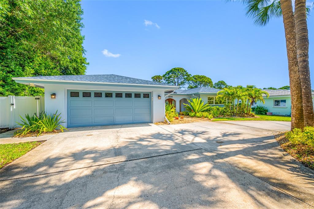 A light blue house with a two-car garage and a concrete driveway under a blue sky — 656 MEHLENBACHER ROAD, BELLEAIR, FL