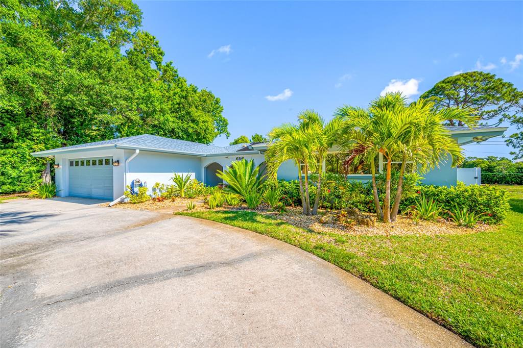 A light blue single-story house with a concrete driveway and palm trees in the yard — 656 MEHLENBACHER ROAD, BELLEAIR, FL