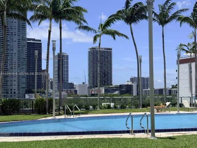 A swimming pool sits in the foreground with tall palm trees and city skyscrapers behind — 601 NE 36th St # 803, Miami FL 33137, MIAMI, FL