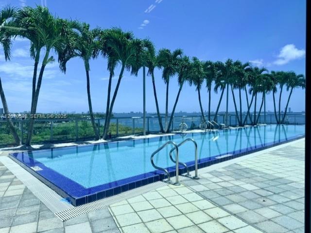An outdoor swimming pool overlooks the ocean, lined by a row of palm trees — 601 NE 36th St # 803, Miami FL 33137, MIAMI, FL