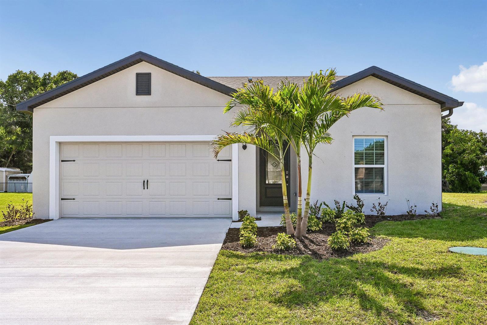 A single-story house with a beige stucco exterior, a two-car garage, and a palm tree — 5808 Sunset Boulevard, Fort Pierce FL 34982, FORT PIERCE, FL