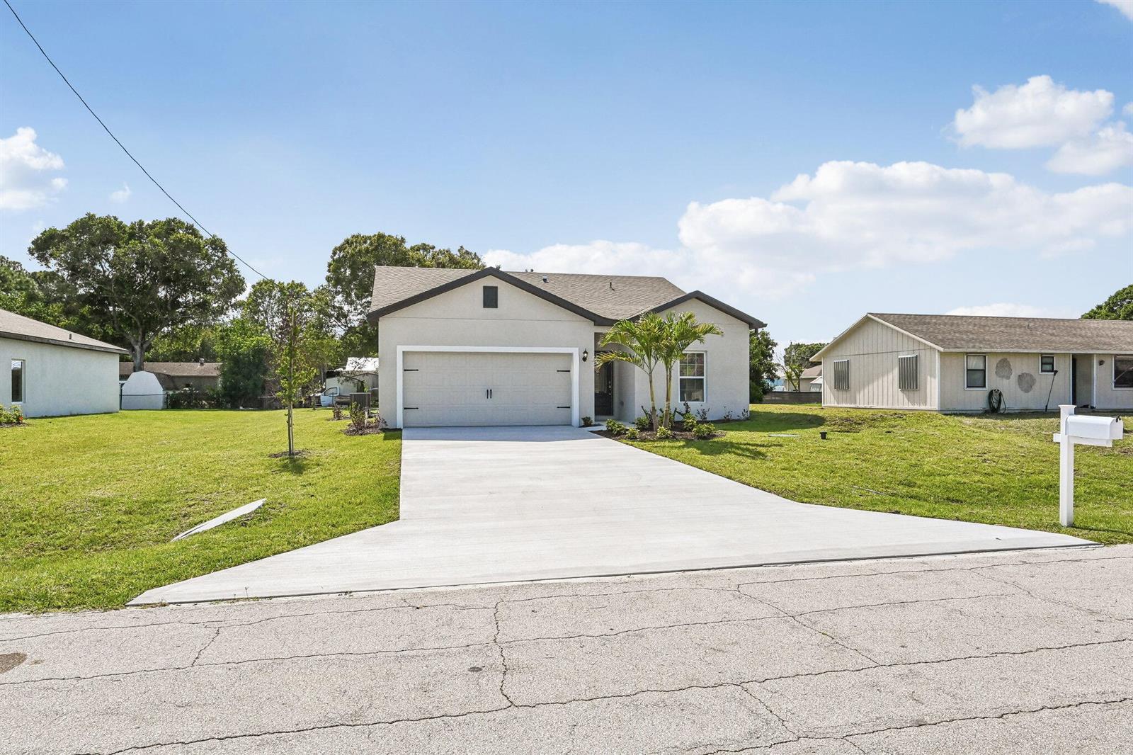 A single-story house with a beige exterior, a two-car garage, and a concrete driveway — 5808 Sunset Boulevard, Fort Pierce FL 34982, FORT PIERCE, FL