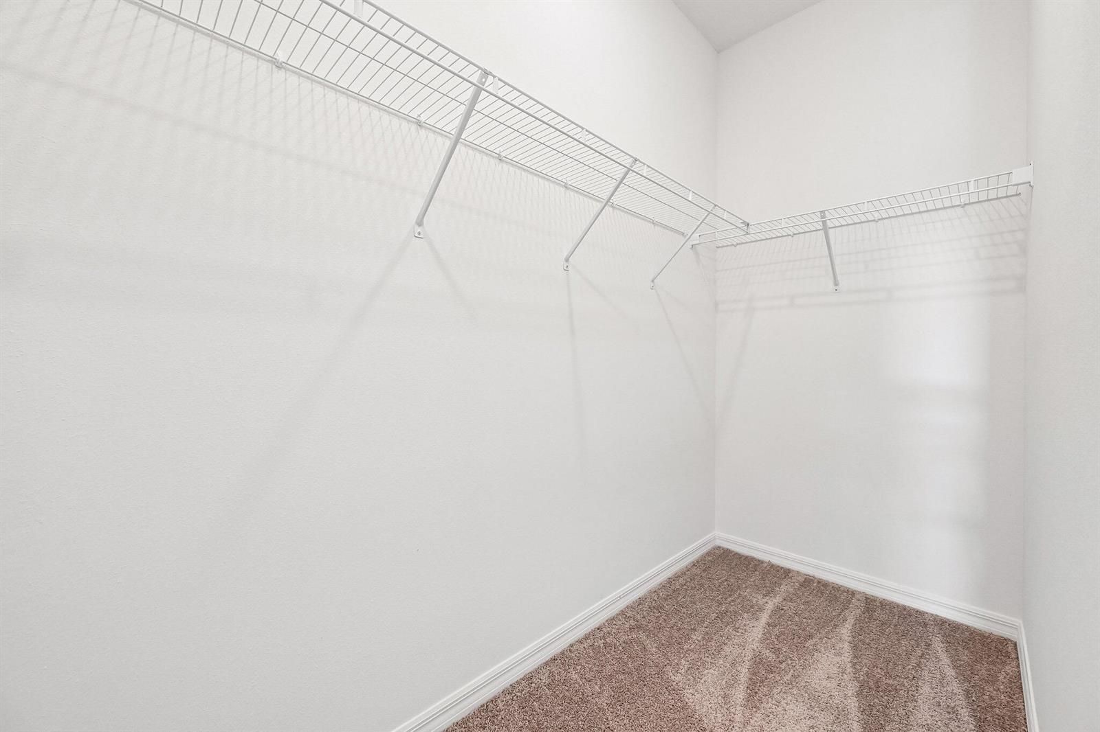 A walk-in closet features white wire shelving and beige carpeted flooring — 5808 Sunset Boulevard, Fort Pierce FL 34982, FORT PIERCE, FL