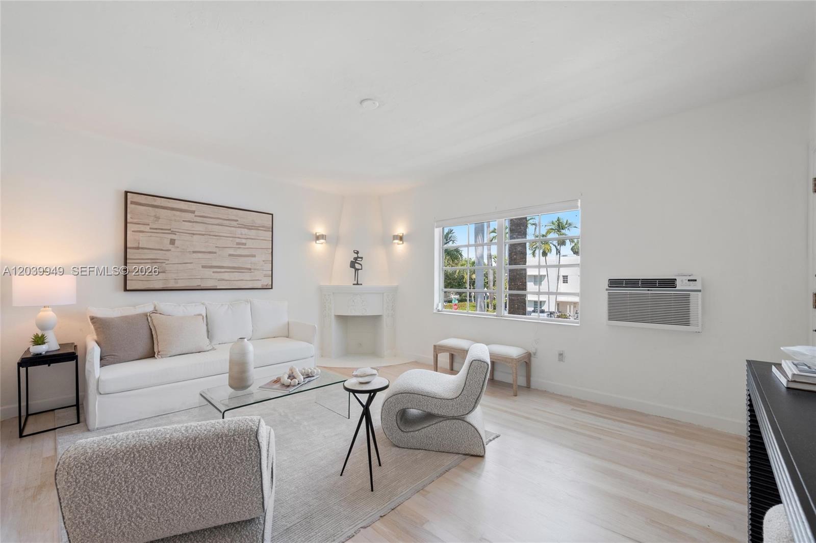 A bright living room features white walls, light wood flooring, a corner fireplace, and furniture — 750 Espanola Way # 8, Miami Beach FL 33139, MIAMI BEACH, FL