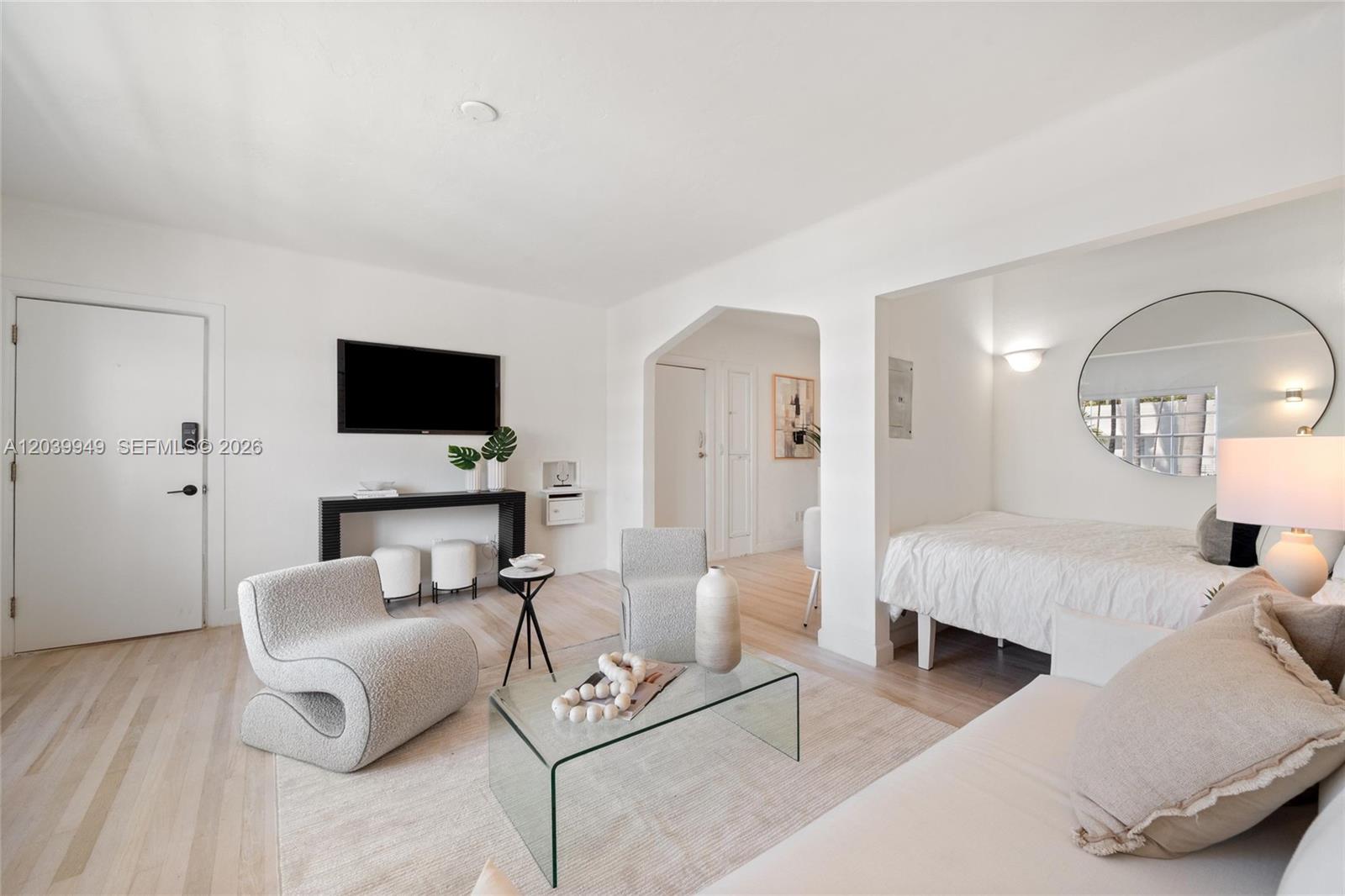A bright living room features light wood floors, a glass coffee table, and an alcove bedroom — 750 Espanola Way # 8, Miami Beach FL 33139, MIAMI BEACH, FL