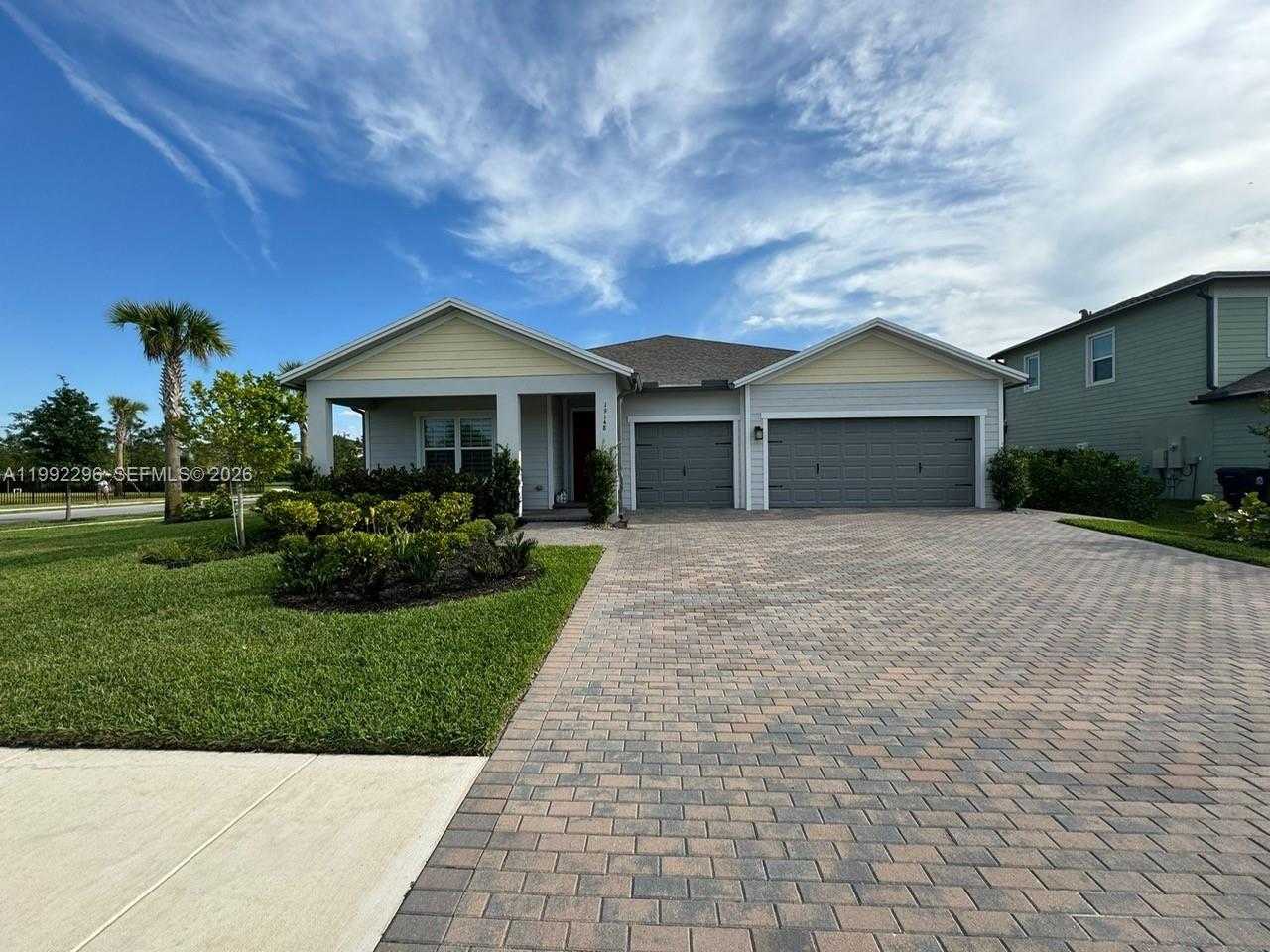 A single-story house with a paved driveway, two garage doors, and a covered front porch — 19148 N Broad Shore Walk, Loxahatchee FL 33470, LOXAHATCHEE, FL