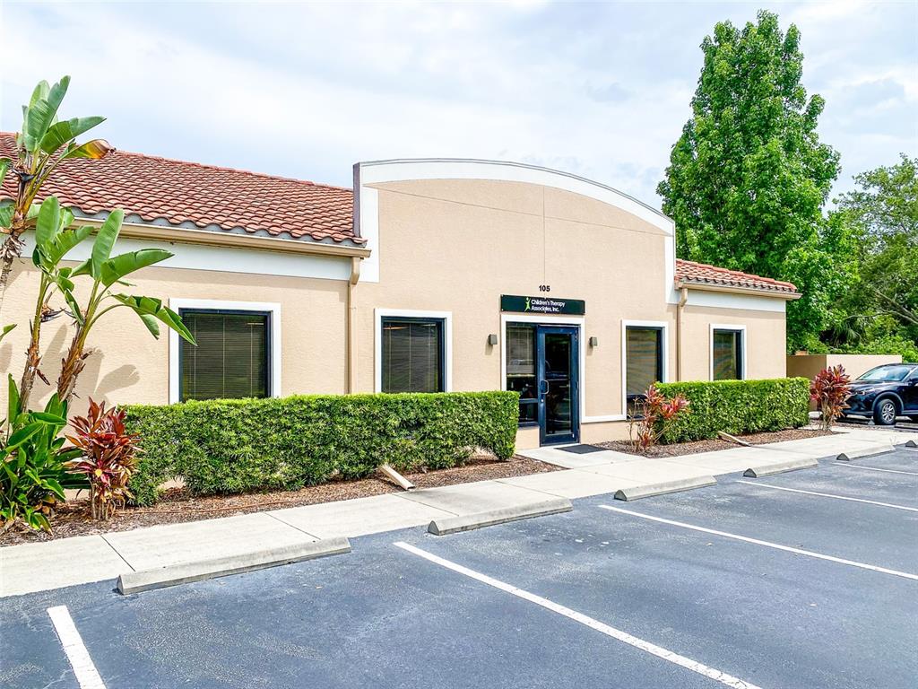 The exterior of a single-story commercial building with a parking lot and manicured hedges — 3911 GOLF PARK LOOP UNIT 105, BRADENTON, FL