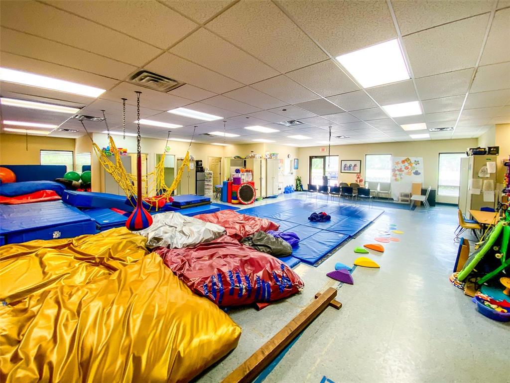 A therapy room features large floor mats, hanging swings, and various sensory play equipment — 3911 GOLF PARK LOOP UNIT 105, BRADENTON, FL