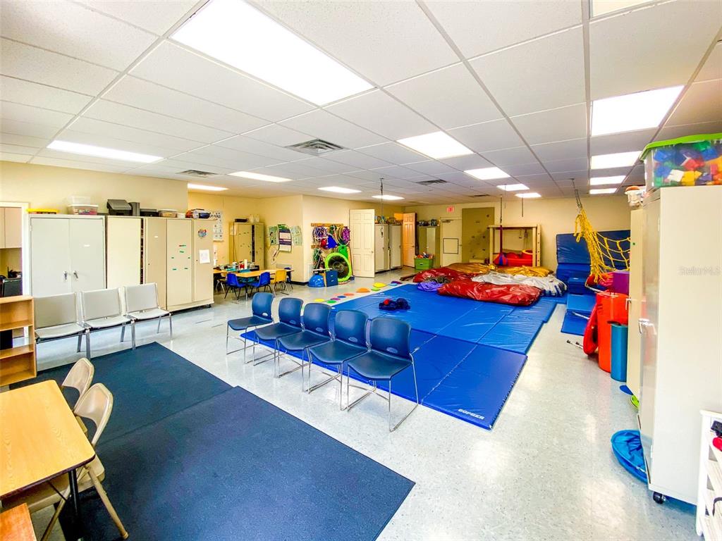 A large classroom features blue floor mats, several chairs, and various play equipment — 3911 GOLF PARK LOOP UNIT 105, BRADENTON, FL