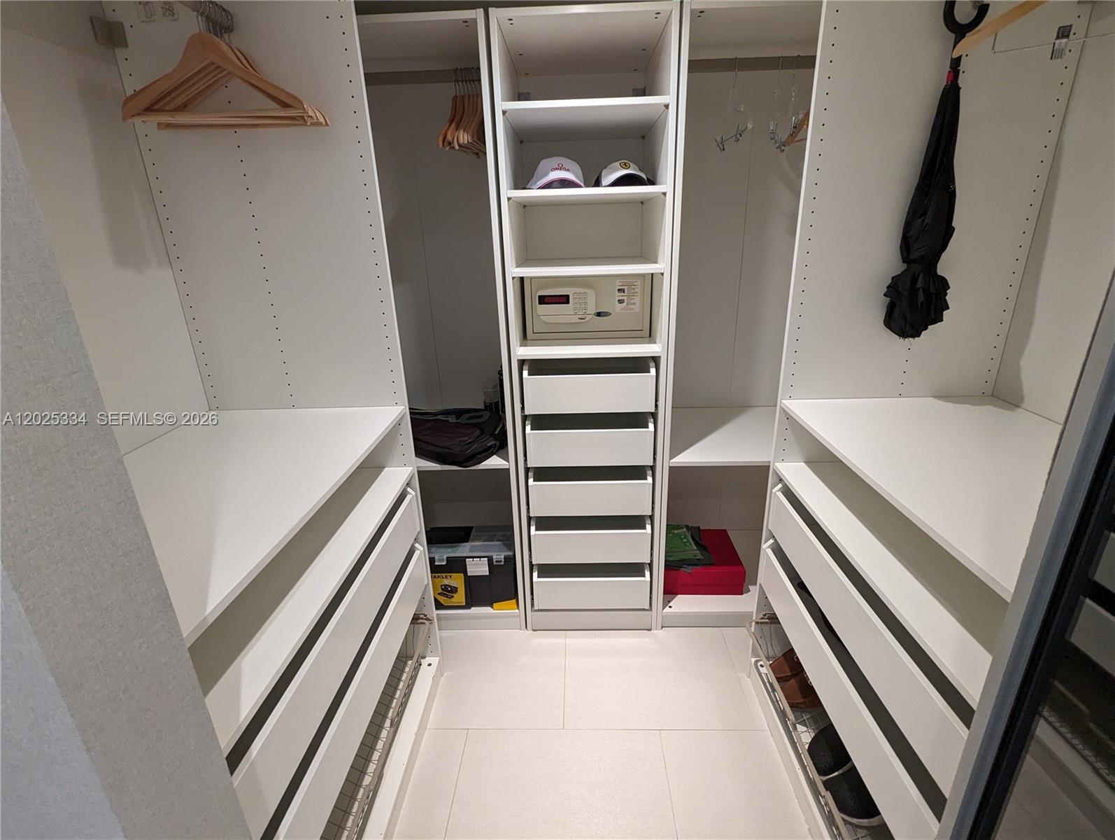 A walk-in closet features white shelving, drawers, a built-in safe, and hanging rods — 2101 Brickell Ave # 1104, Miami FL 33129, MIAMI, FL