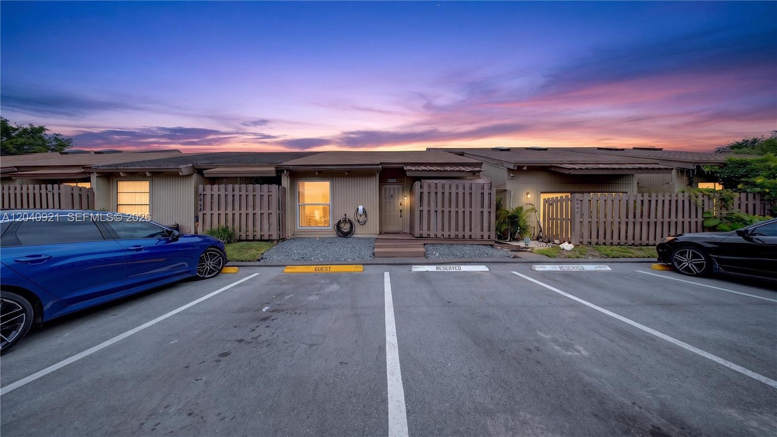 A single-story townhouse exterior features a wooden fence, a guest parking space, and a sunset — 8046 SW 21st Ct, Davie FL 33324, DAVIE, FL