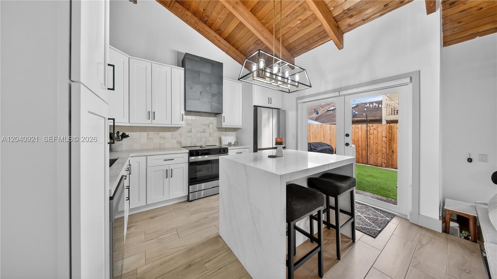 A modern kitchen features white cabinetry, a marble-topped island, and a vaulted wood-beamed ceiling — 8046 SW 21st Ct, Davie FL 33324, DAVIE, FL