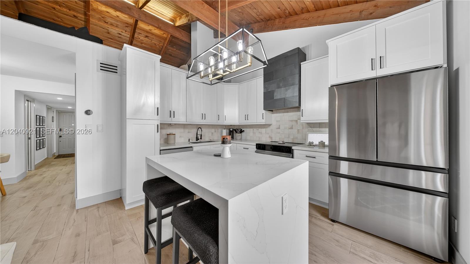 A modern kitchen features white cabinetry, a marble-topped island, and a vaulted wood-beam ceiling — 8046 SW 21st Ct, Davie FL 33324, DAVIE, FL