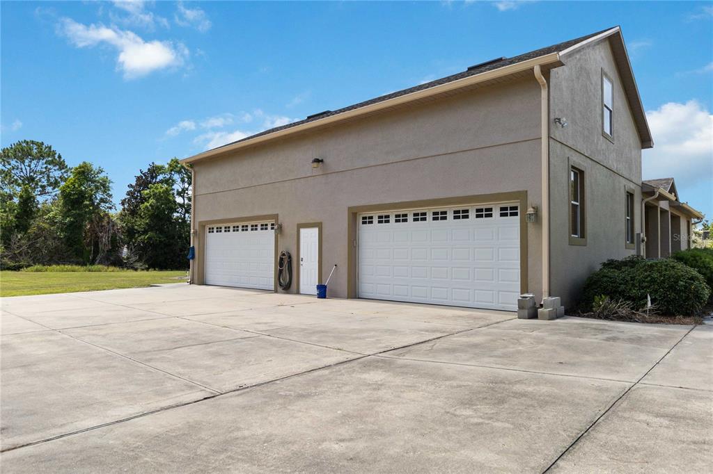 A beige two-story house features a three-car garage and a large concrete driveway — 1300 S NARCOOSSEE ROAD, ST CLOUD, FL