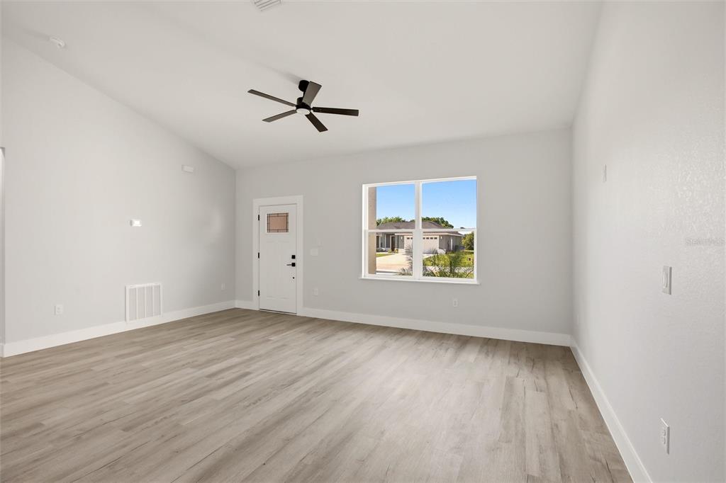 An empty room with light gray walls, wood-look flooring, a ceiling fan, and a window — 1313 BLUE HERON DRIVE, SEBRING, FL